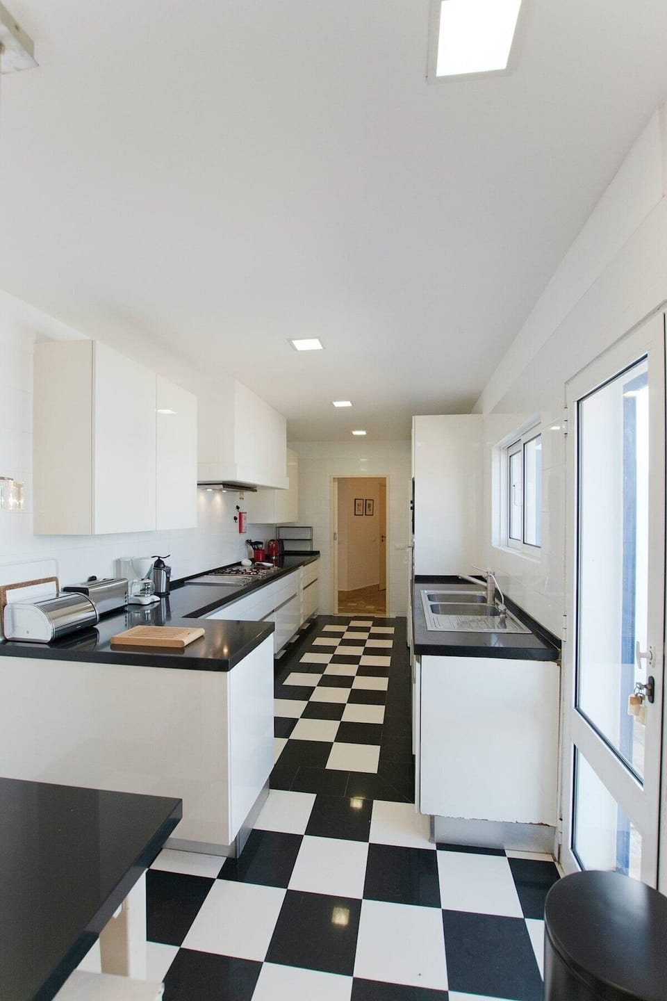 Modern galley kitchen with black and white checkerboard floor — Villa Alfarrobeira, holiday villa in Lagos
