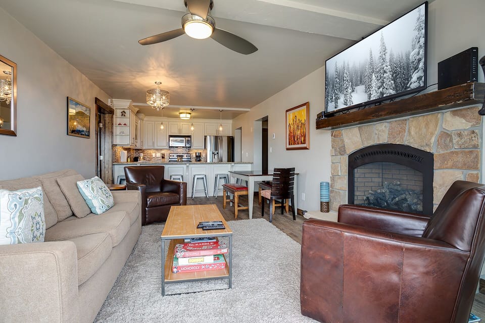 Your open-concept retreat blends comfort with alpine charm, featuring a cozy fireplace and modern kitchen perfect for mountain getaways.