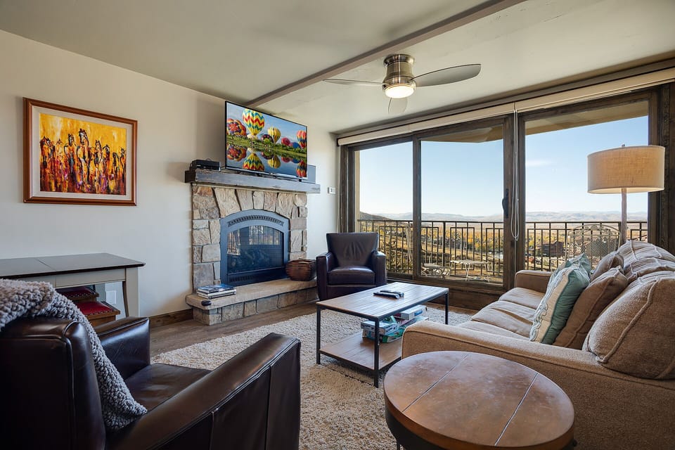 Sink into plush seating and enjoy sweeping vistas through floor-to-ceiling glass doors. Your living room features a cozy stone fireplace, modern entertainment, and a private balcony where stunning valley views await.