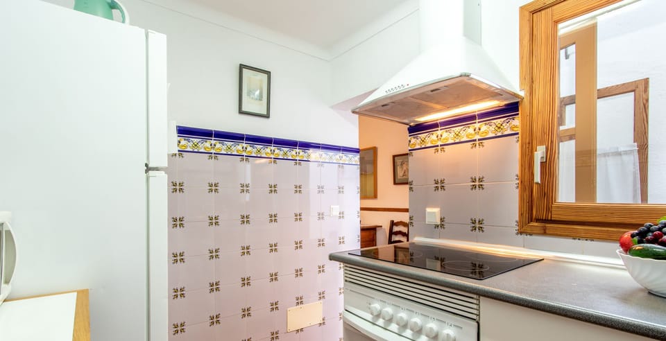 Traditional kitchen in a Mallorcan village house with decorative tiles, functional countertop and natural light.