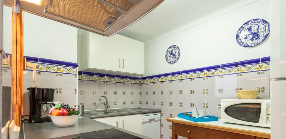 Fully equipped kitchen in a Mallorcan village house with traditional tiles, integrated appliances and a functional workspace.