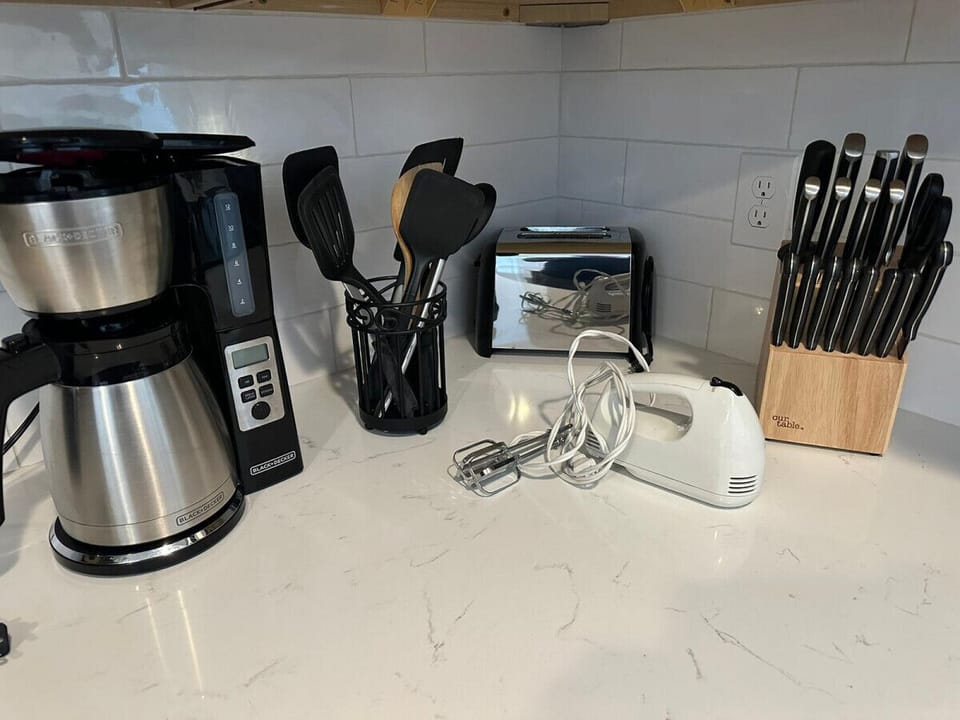 Variety of knives with different blade shapes and sizes, versatile cooking utensils, coffee maker, toaster, and electric mixer.