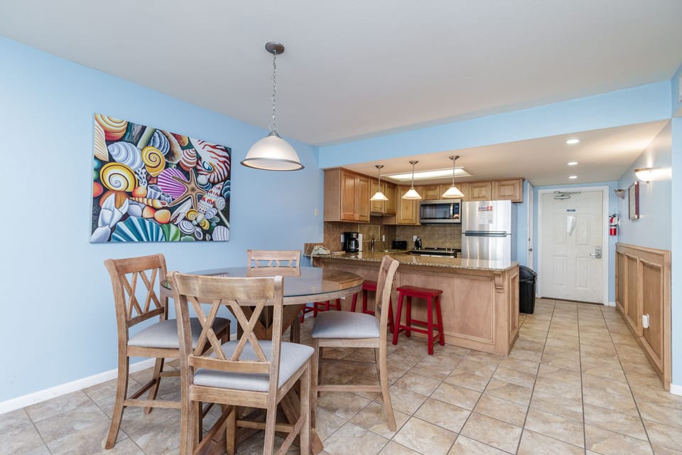 Your open kitchen and dining space features warm wood cabinets, granite countertops, and colorful artwork that creates a welcoming atmosphere for meals together.