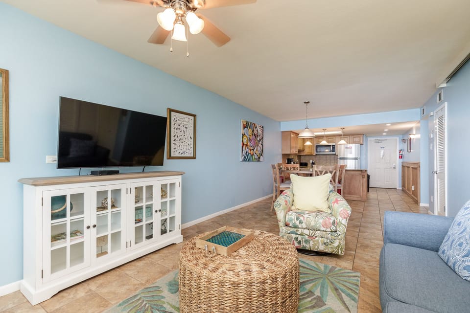 Unwind in your coastal-inspired living space with soothing blue walls, comfortable seating, and entertainment center for perfect relaxation after beach days.
