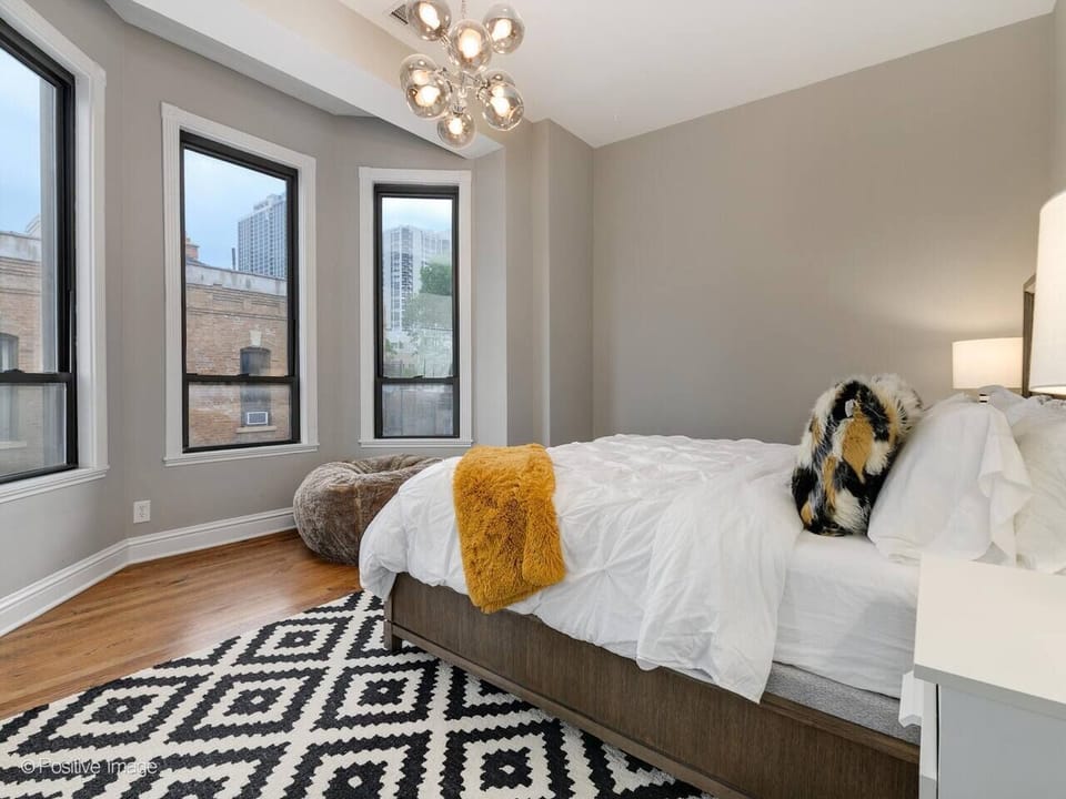 This is the first bedroom and it contains a high-end king sized bed with plush mattress. Solid wood bed frame and bay windows overlooking quaint Schiller Street in the Old Town neighborhood of Chicago.