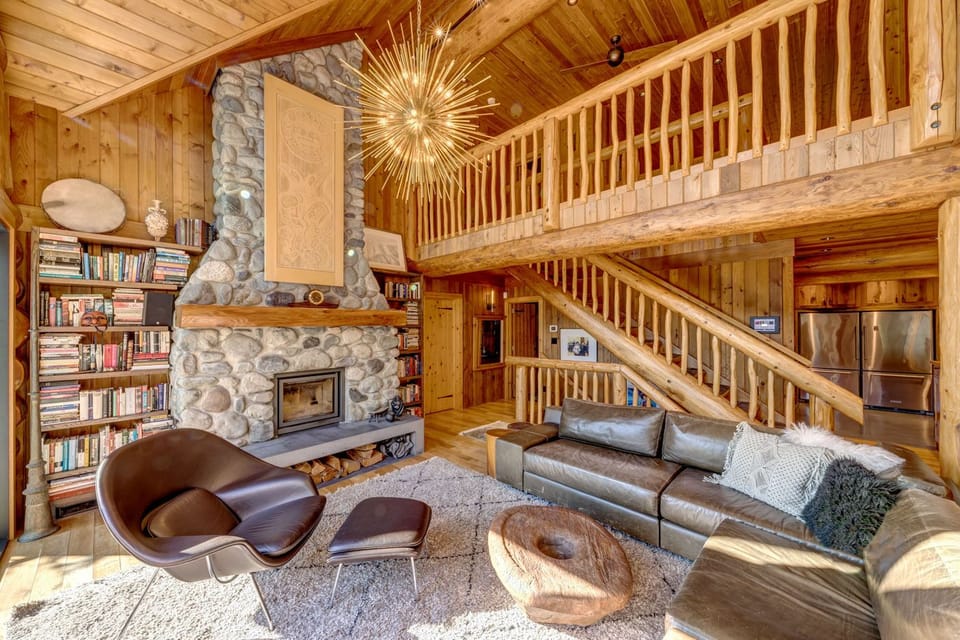 Natural light floods the open concept living area featuring vaulted ceilings and a wood burning fireplace