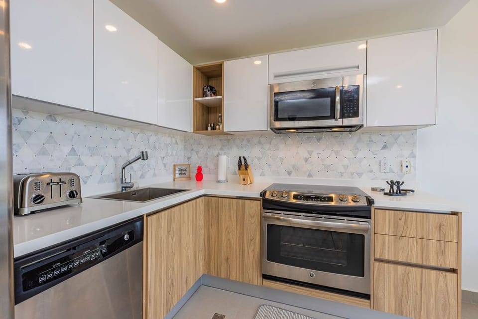 You'll love this modern, fully equipped kitchen with sleek stainless appliances, marble backsplash, and all the essentials for cooking your favorite meals at home.