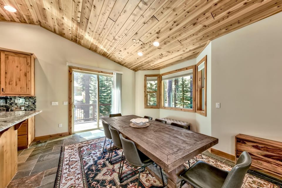 Gather around this stunning rustic dining table beneath soaring wood-planked ceilings, where your meals feel elevated by forest views.