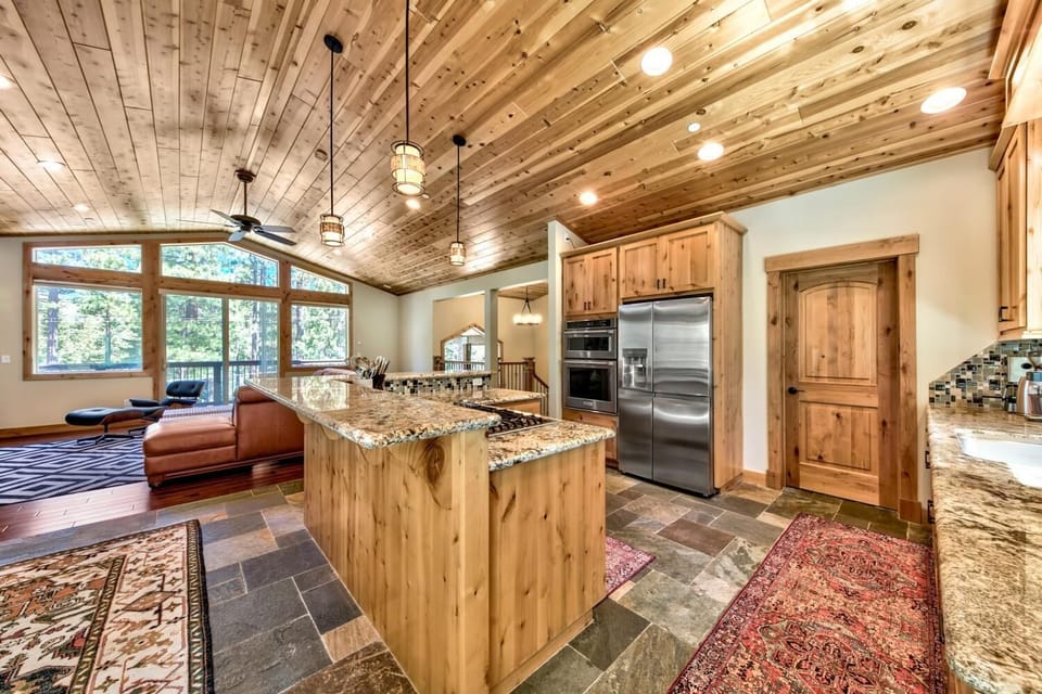 Your chef's dream awaits in this stunning open kitchen with granite countertops, stainless steel appliances, and rustic wood beams overhead.
