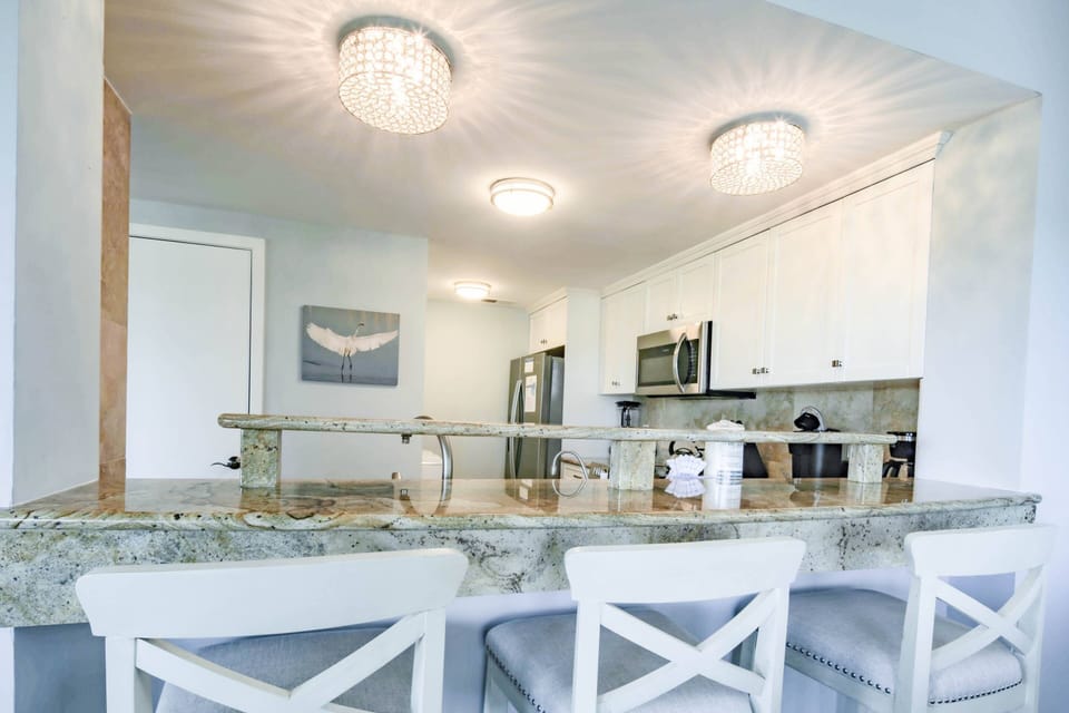 The renovated kitchen features granite counters, stool seating and stainless steel appliances.