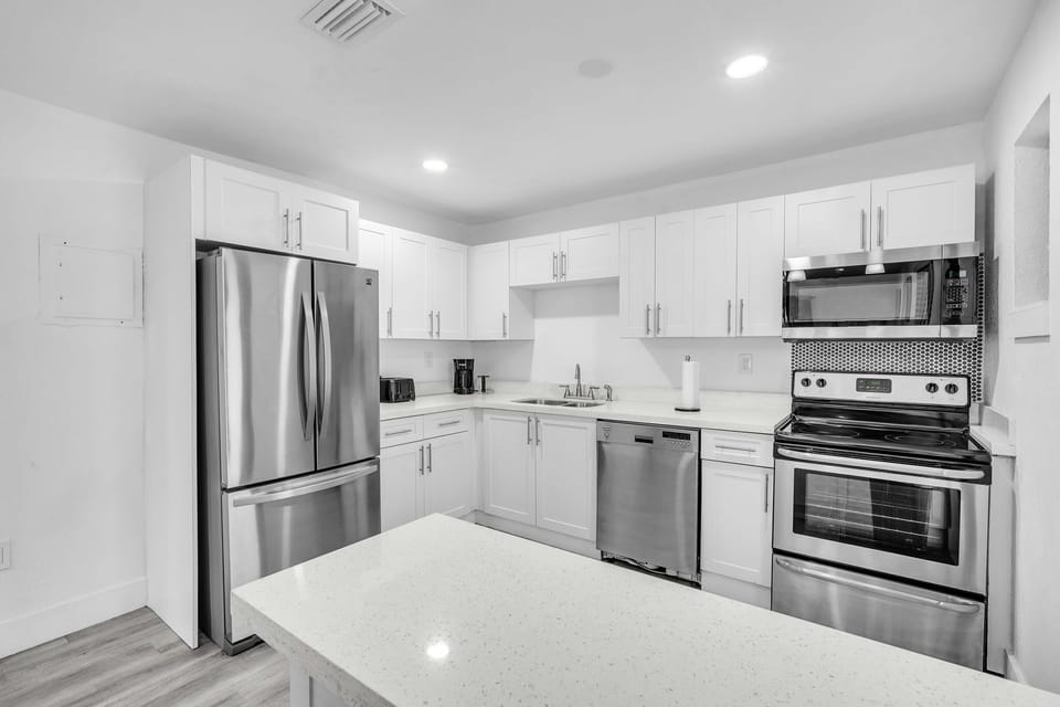 A sleek, clutter-free kitchen with all the necessary amenities, including a spacious refrigerator, dishwasher, and essential cooking tools.