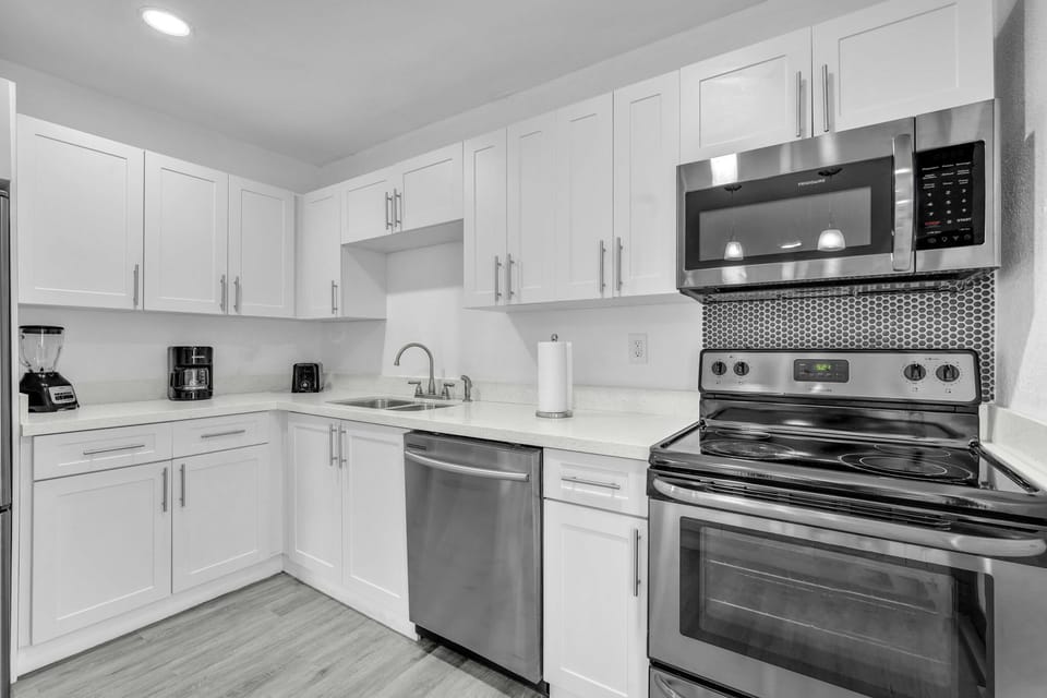 Ample kitchen space, thoughtfully furnished with stainless steel appliances, a sizable refrigerator, and all the essential kitchen necessities.