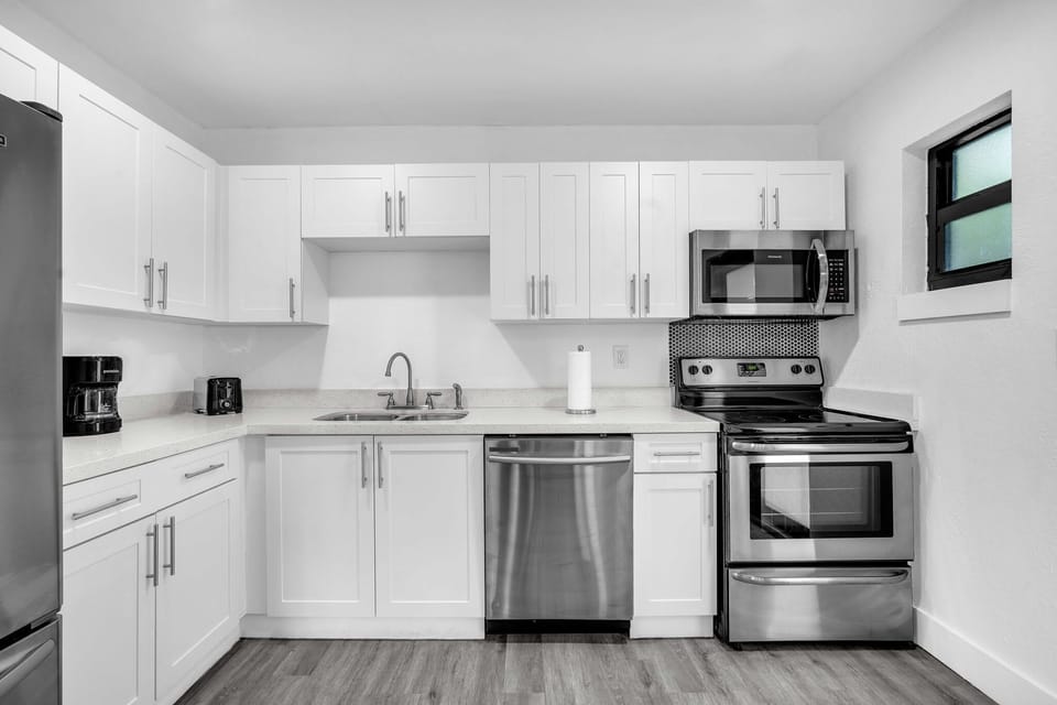 Ample kitchen space, thoughtfully furnished with stainless steel appliances, a sizable refrigerator, and all the essential kitchen necessities.