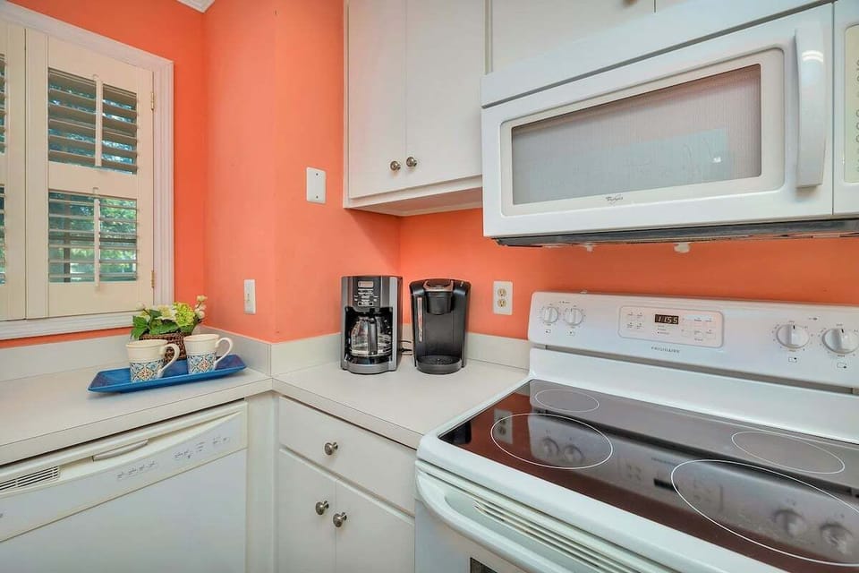 Kitchen with white cabinets, coral walls, and cooktop