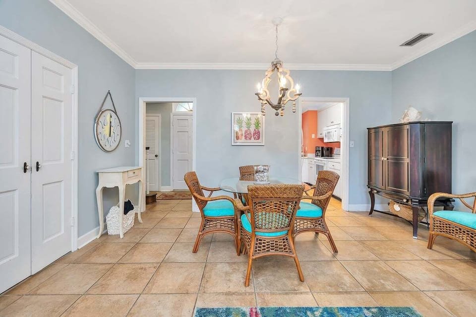 Dining area with wicker chairs, chandelier, and tile floors