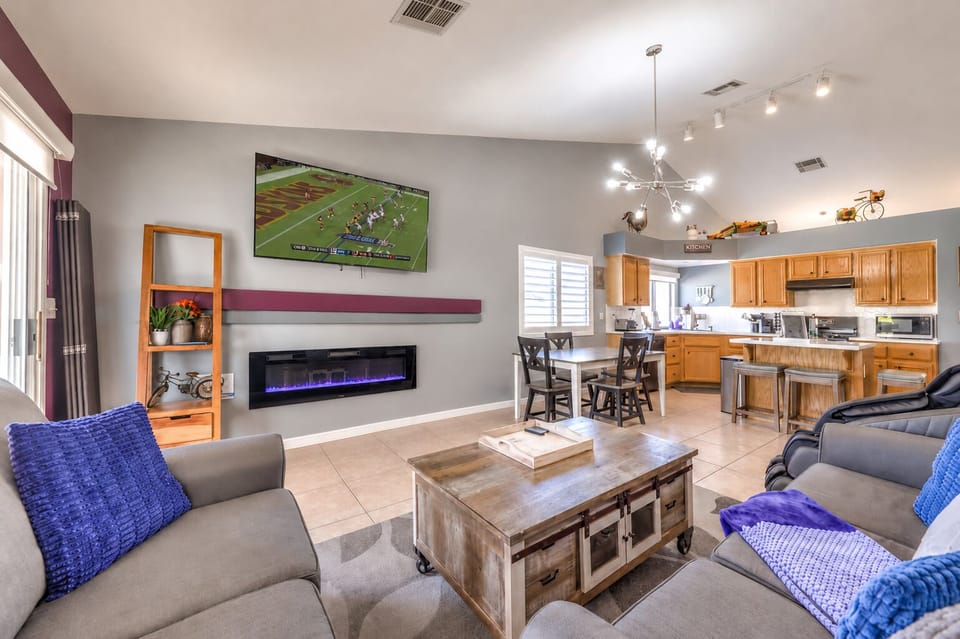 Bright open living room with fireplace, TV, and spacious kitchen