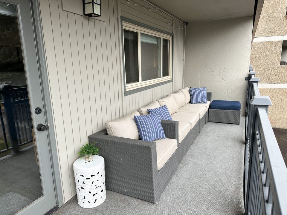 Private covered balcony with sofa, oversized chair, ottoman and bistro table