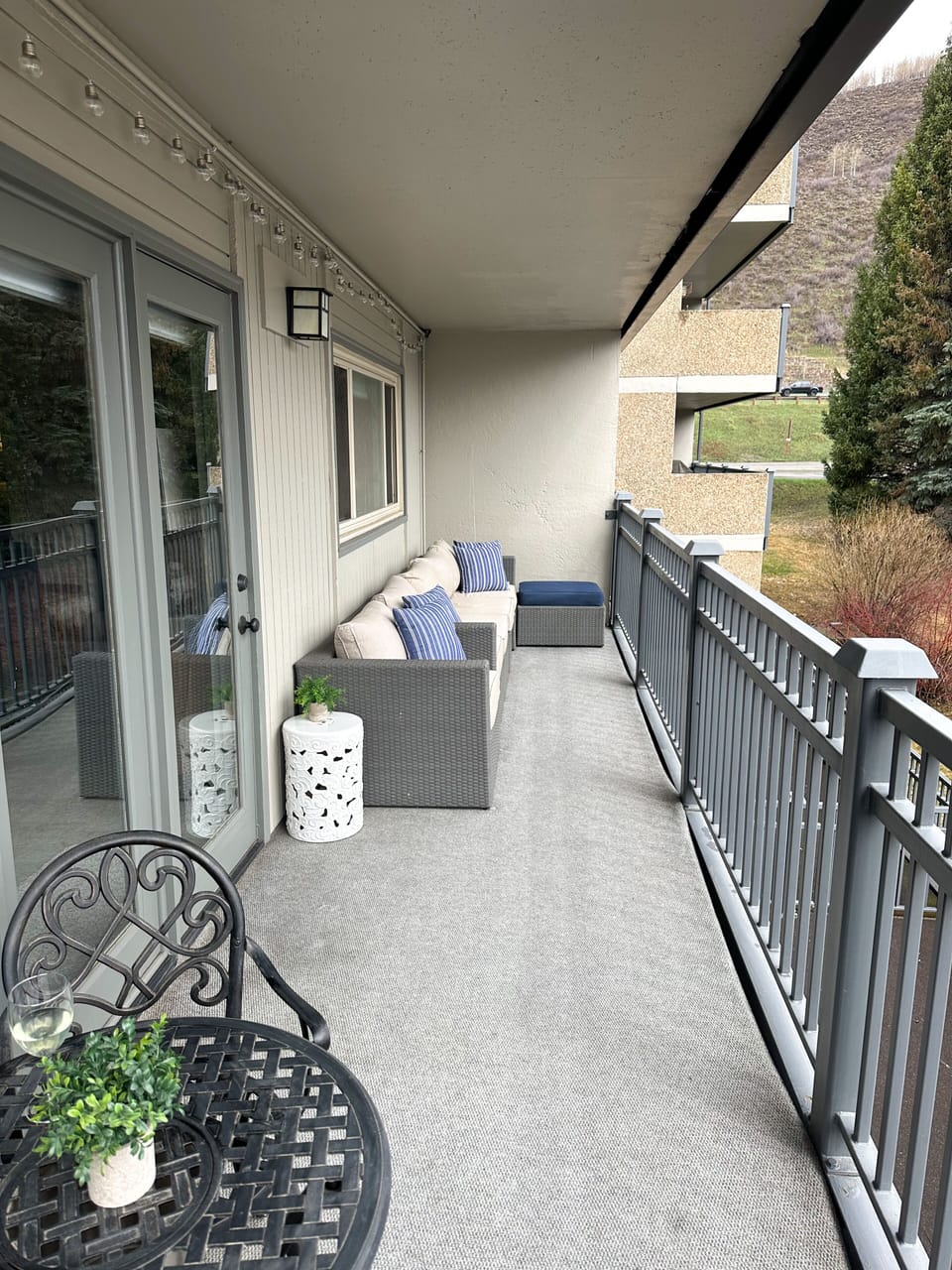 Private covered balcony with sofa, oversized chair, ottoman and bistro table