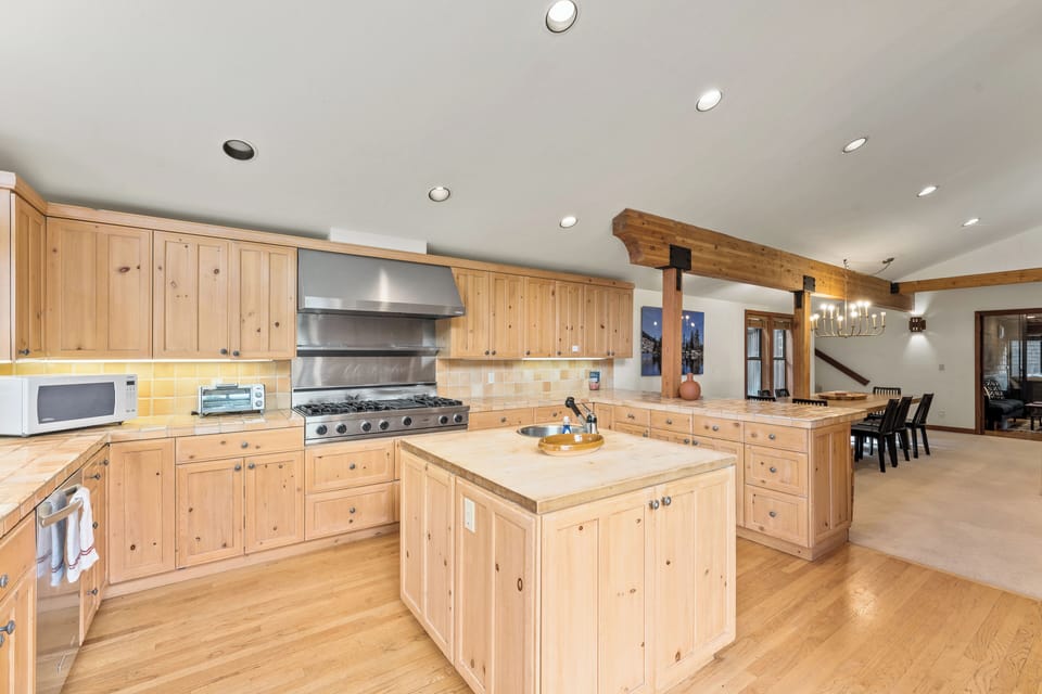 Chef's kitchen fully equipped for culinary adventures features a gas range, dishwasher and butcher block island. 