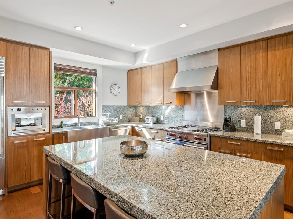 Gourmet professional kitchen with top-of-the-line stainless steel appliances, a built-in espresso machine and large island seating.
