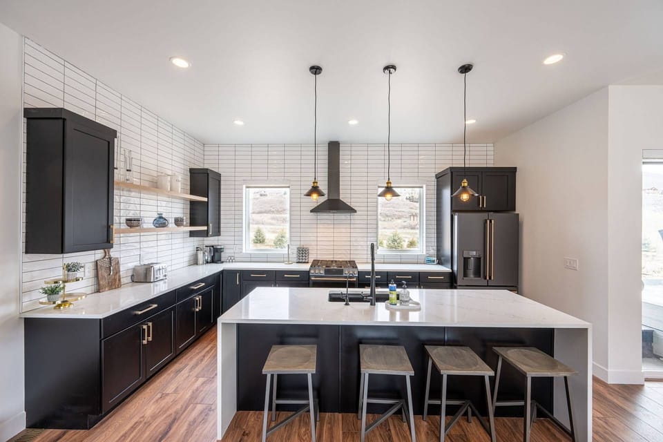 Gourmet kitchen featuring custom lighting, white quartz waterfall edge breakfast bar, high end appliances, everything is here