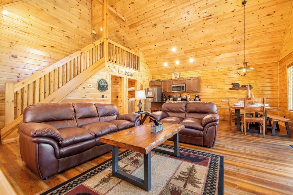 Relax in your cozy cabin's open living space where rich leather sofas invite you to unwind by the warm wood-paneled walls.