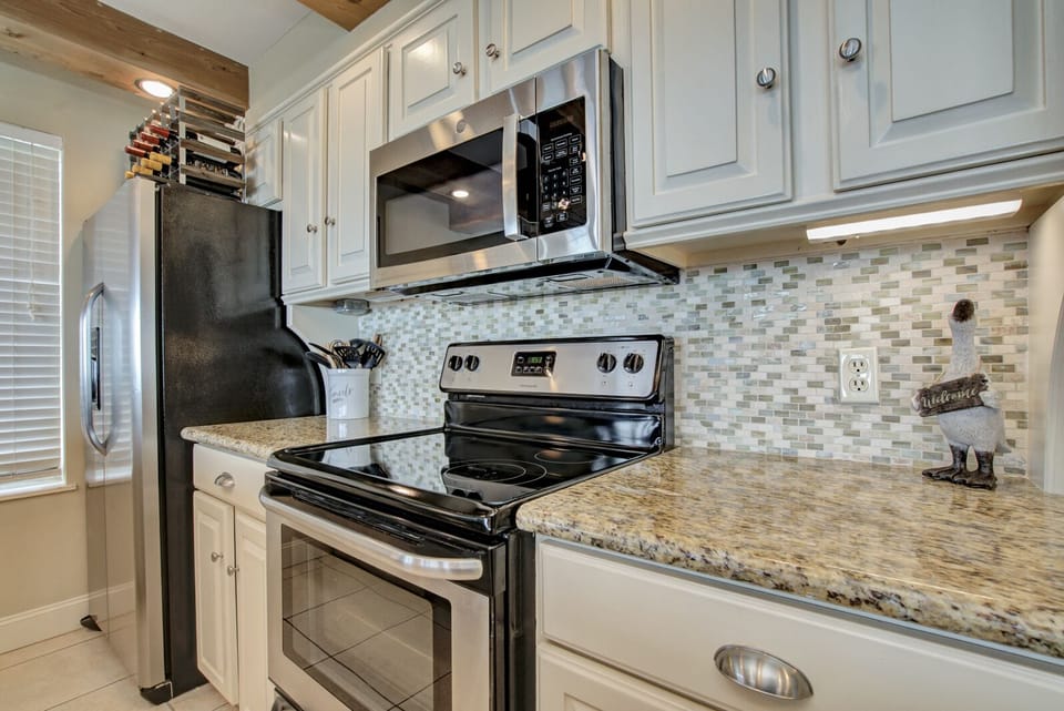 Microwave, conventional oven, and electric stove complemented by granite countertops.
