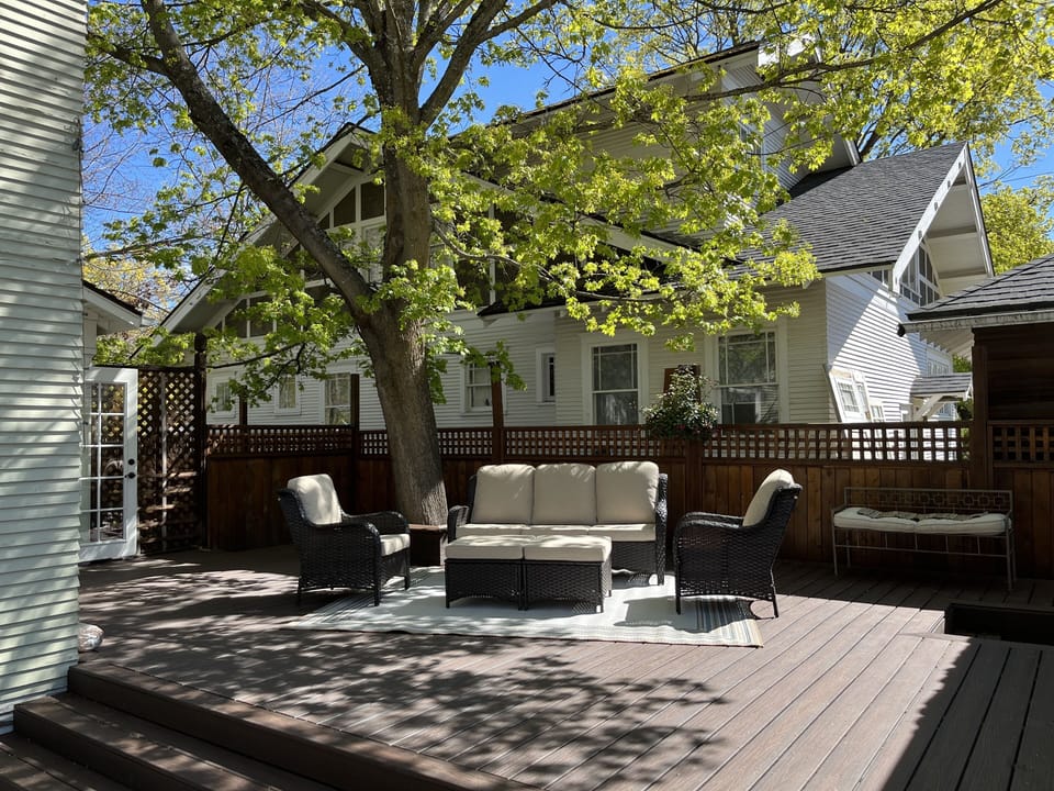 New deck with comfortable outdoor seating under a large shade tree in backyard 