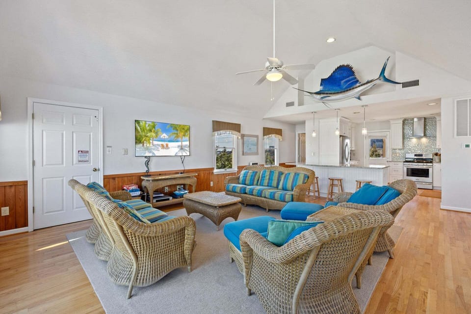 The top-level living area features high ceilings, abundant natural light, and comfortable seating for the whole family.