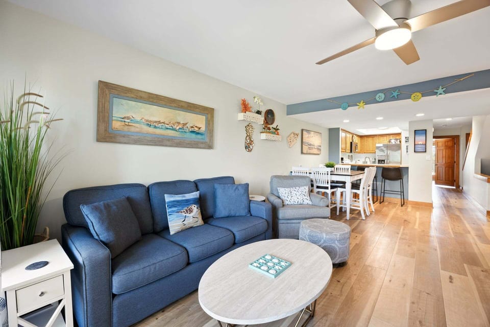 Bright living area with updated furnishings, a 55" TV, and access to the covered ocean-view deck.