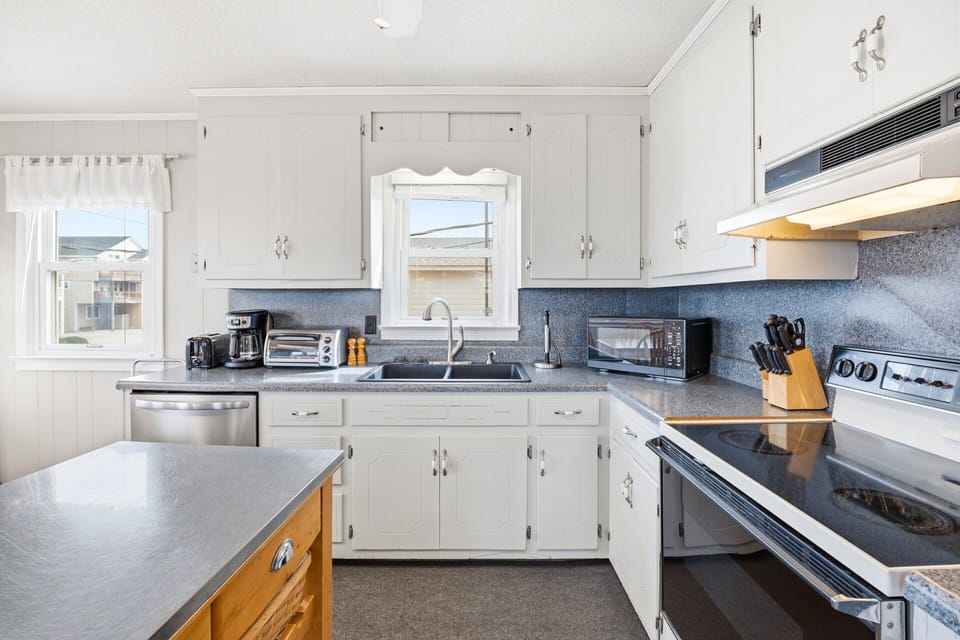 The fully stocked kitchen includes a full-sized refrigerator, microwave, icemaker, and dishwasher, making meal prep easy for families.