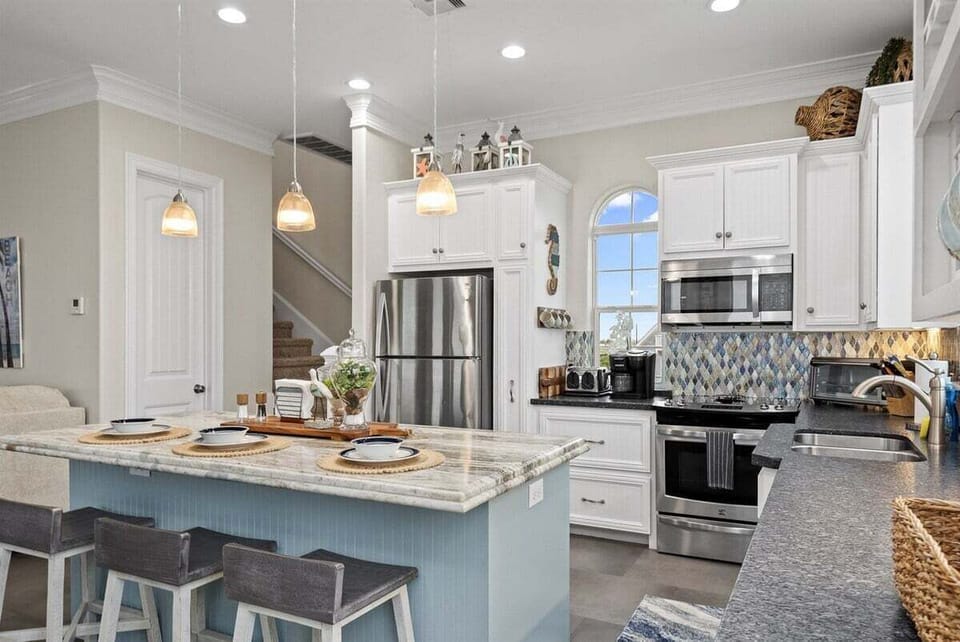 Bright gourmet kitchen with stainless steel appliances and breakfast bar in Galveston beach house.