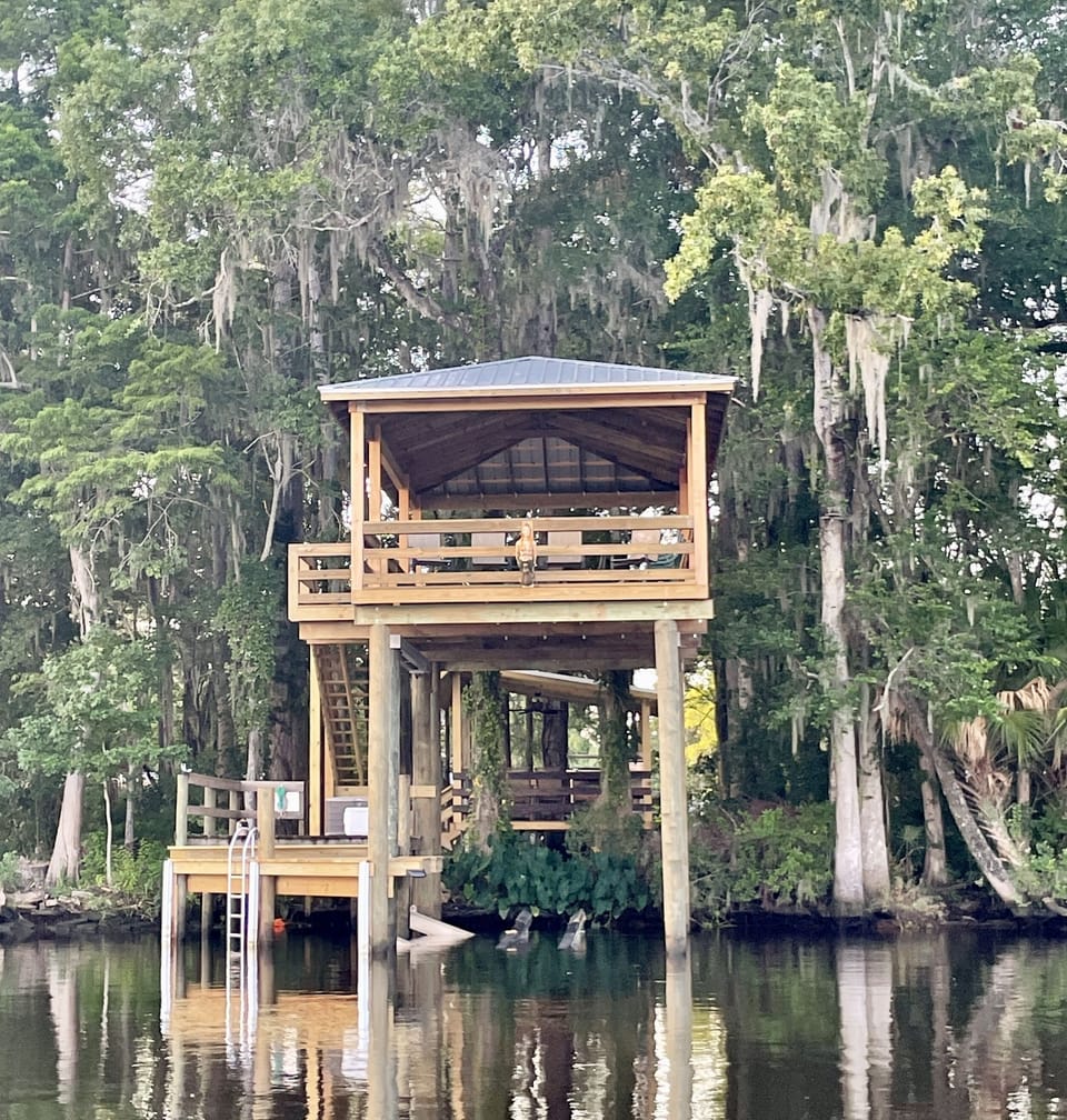Two story boathouse with a patio table & extra chairs. 