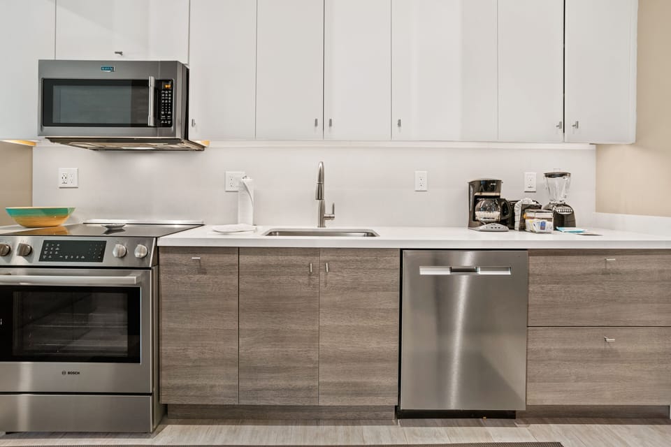 Your modern kitchen features stainless steel appliances, sleek white countertops, and ample storage with elegant two-tone cabinetry, making meal prep a breeze.