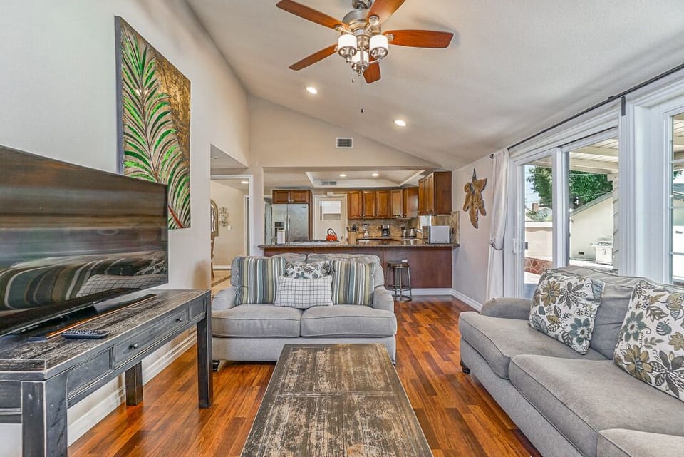 - Living room with cozy sofas and flat screen TV for guests   - Ceiling fan keeps space cool with natural light flowing in   - Open layout connects to kitchen for easy group gatherings