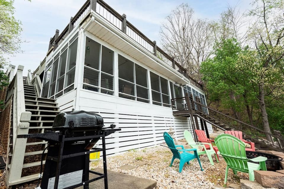 The side yard includes additional colorful outdoor chairs, a grill, and access along the screened lakefront structure.