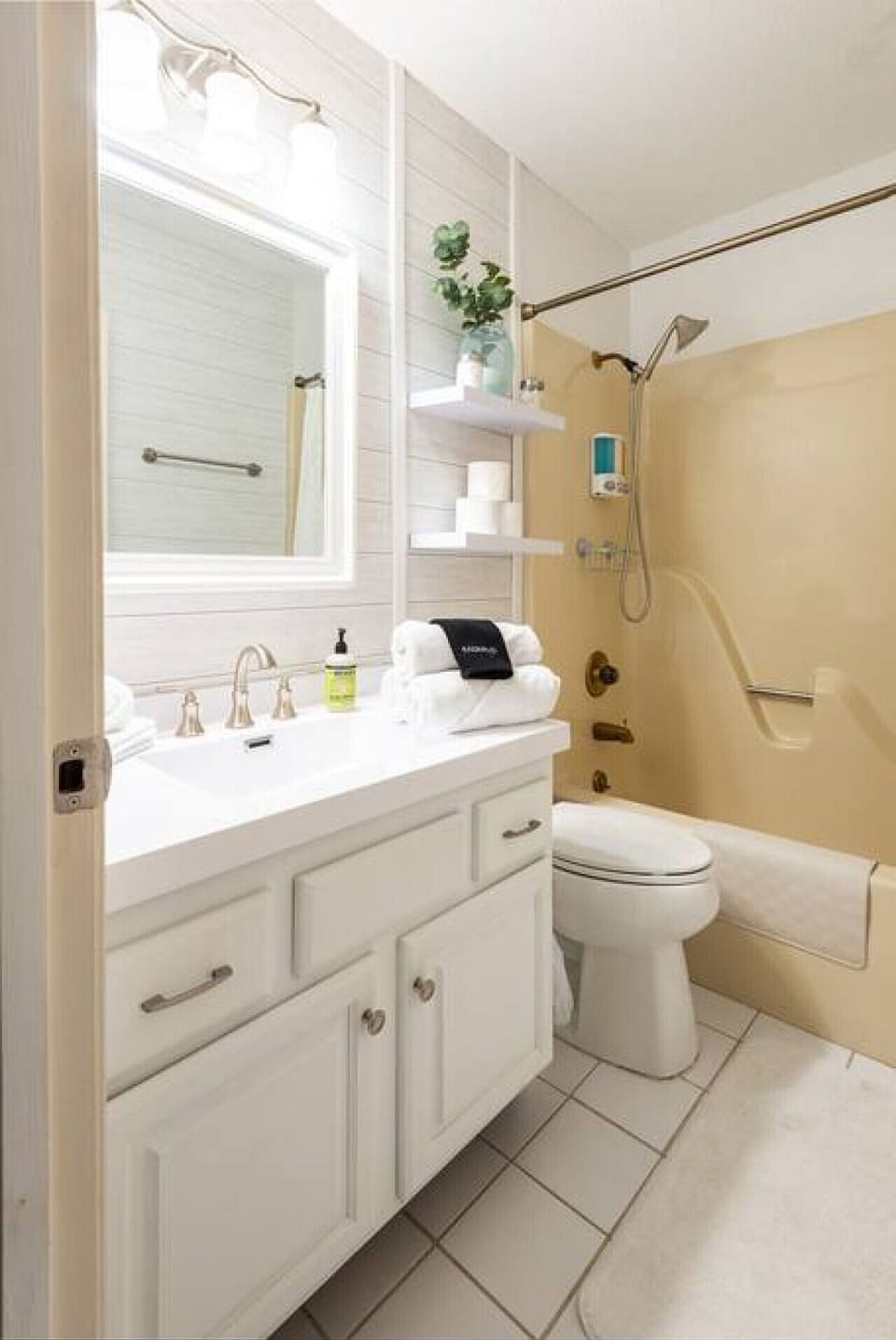 The first full bathroom features a bright vanity, toilet, and tub-shower combination with convenient grab bars.