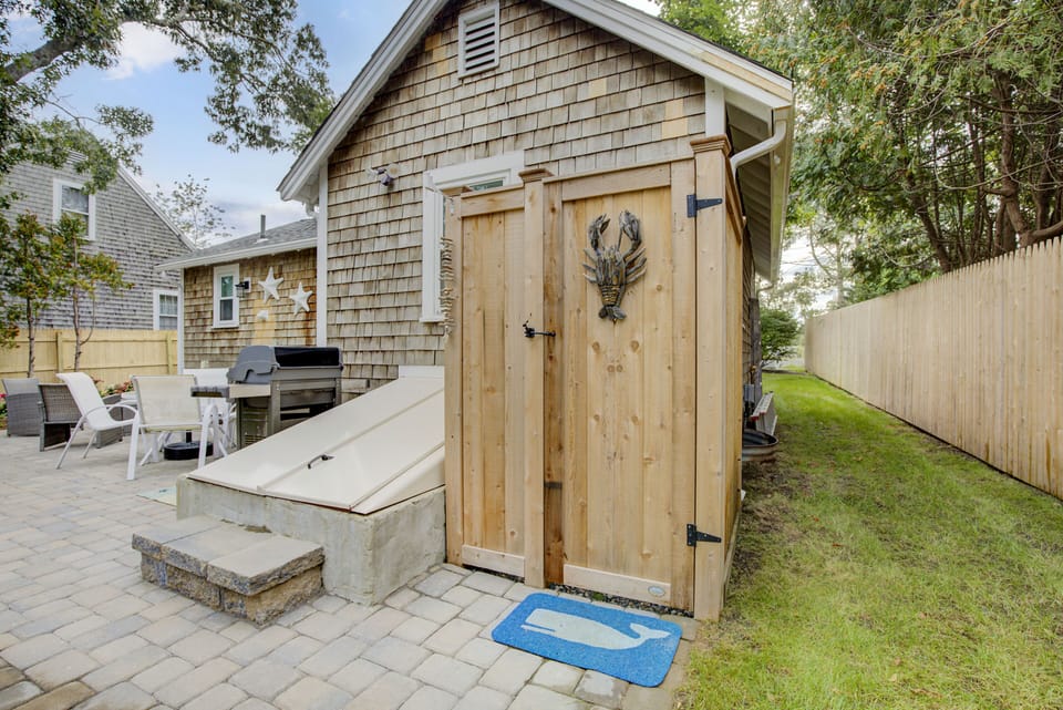 Large backyard patio with outdoor shower, Weber natural gas grill, and seating.