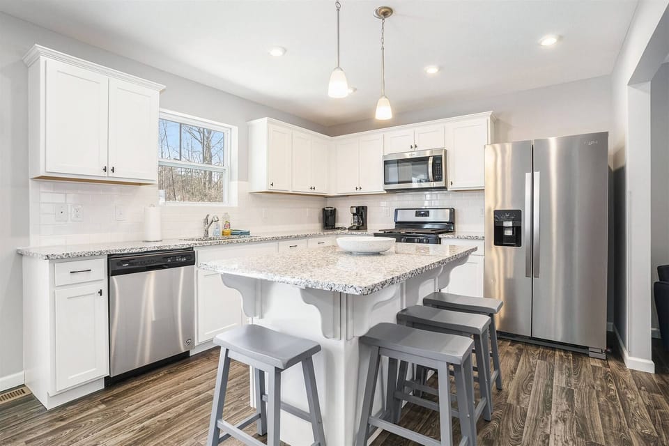 Fully equipped kitchen with stainless appliances, a spacious island, and seating for the whole group.