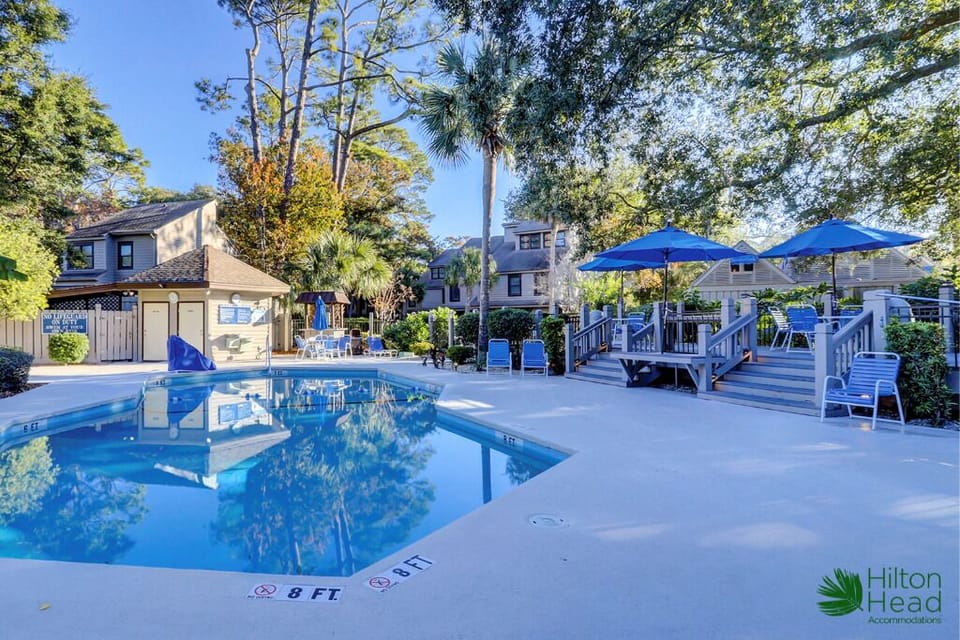 Lounge poolside under shady trees and bright blue skies.