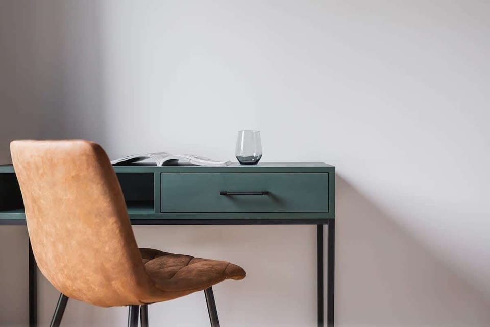 A small home office setup with a desk and chair, perfect for work or study, placed against a clean white wall.