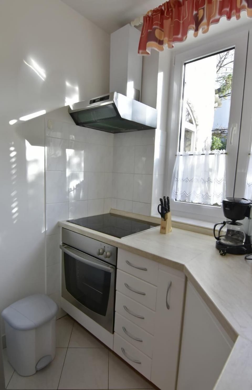 The kitchen with a hob, extractor hood, oven and coffee machine