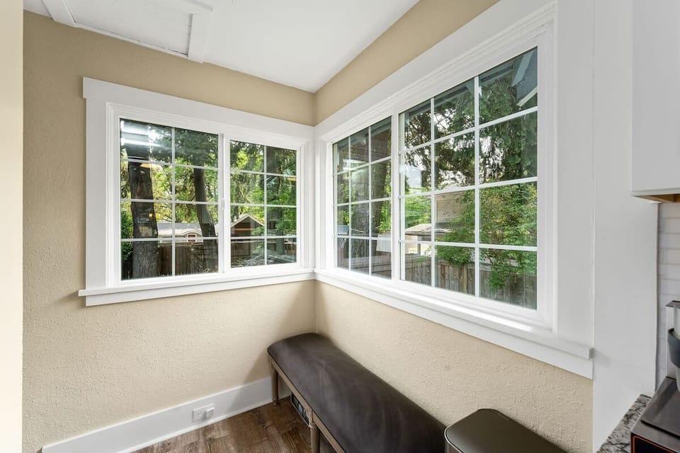 Relax in your bright corner nook with expansive windows framing peaceful garden views and a cozy bench for morning coffee.