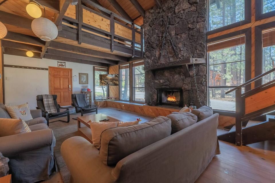 Living area with high ceilings, tall windows and a warming fireplace.