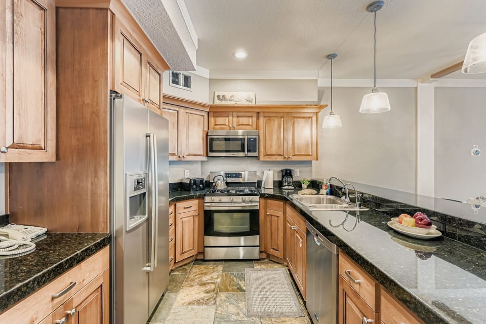 Your fully equipped kitchen features warm wood cabinetry, granite countertops, and stainless steel appliances for all your culinary needs during your stay.