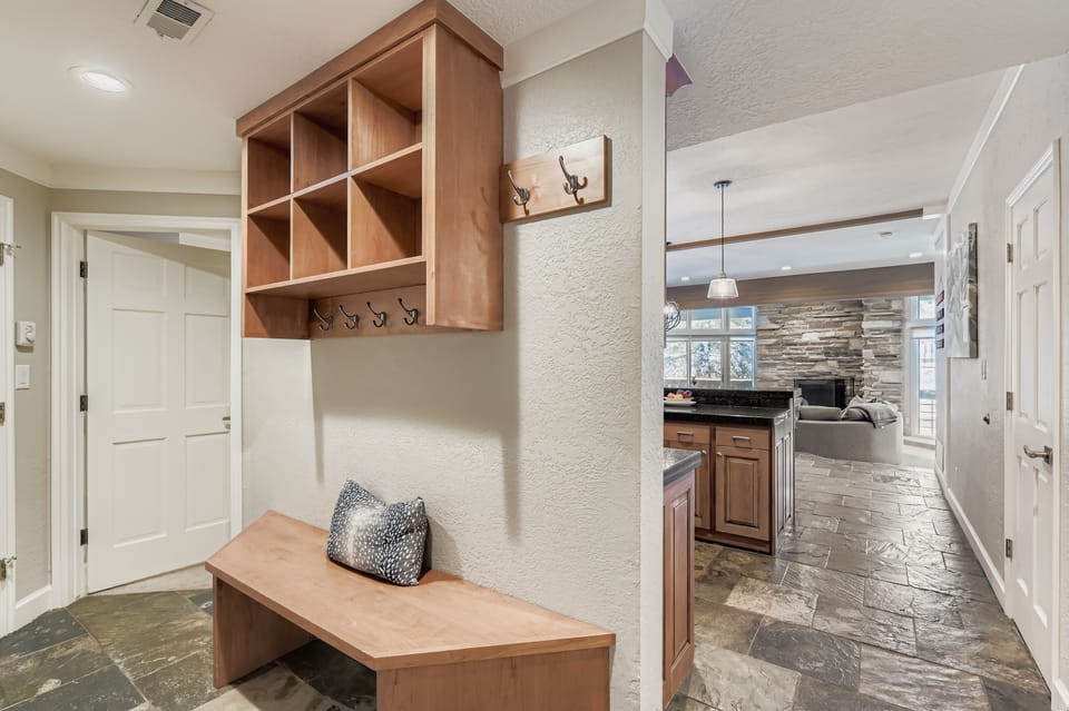 A welcoming entryway with custom wood storage, cozy bench seating, and warm tones flows into your mountain retreat's open living spaces.