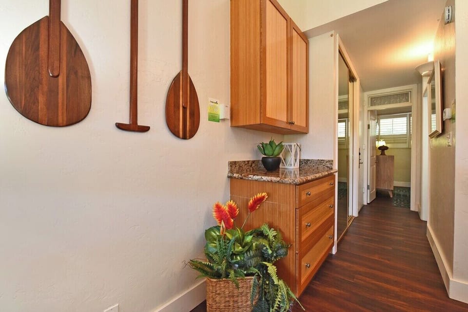 Step into a welcoming hallway with wall-mounted paddles, granite counters, and a basket of tropical blooms.