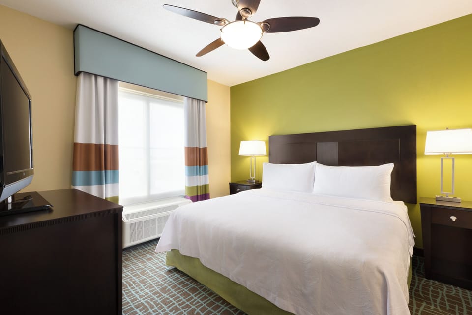 Unwind in a crisp, sunlit bedroom with cozy bedside glow.