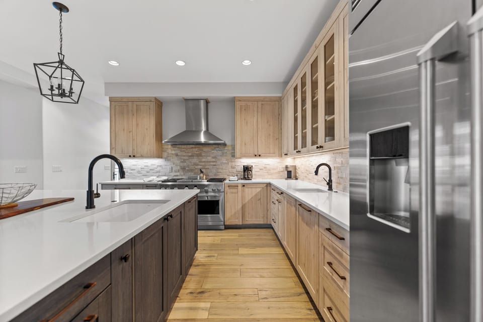Full kitchen with stainless steel appliances, 2 sinks, and a large kitchen island with breakfast bar seating for casual dining.