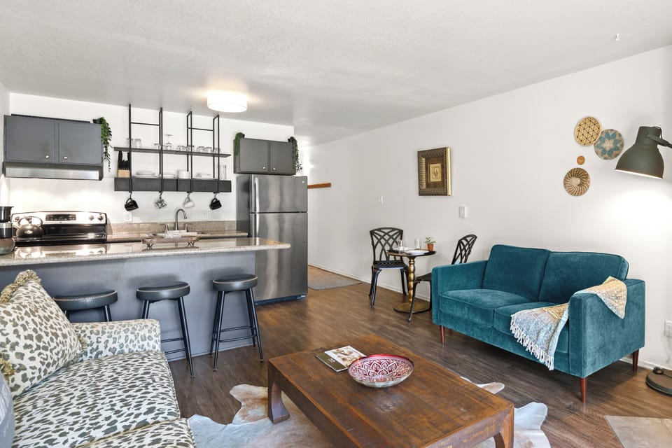The living room offers two colorful couches and an open concept kitchen.